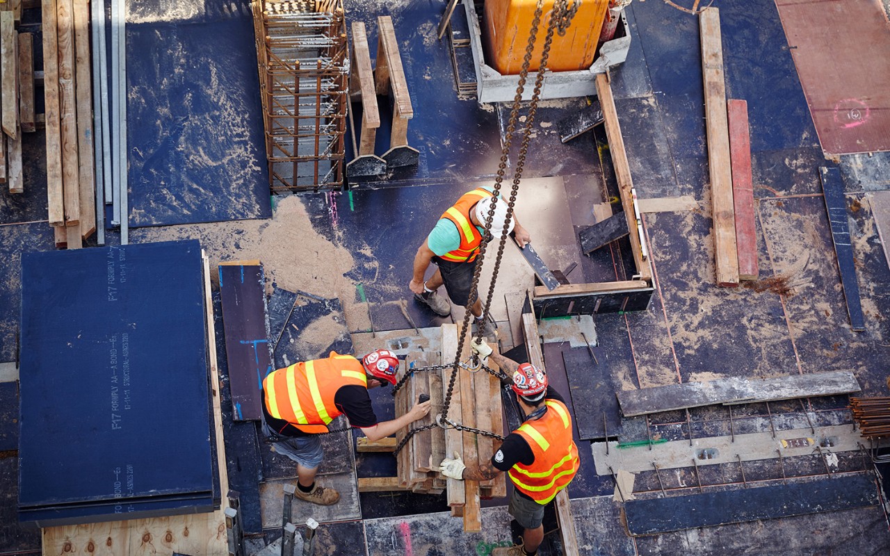 Three tradesmen on a site controlling a crane